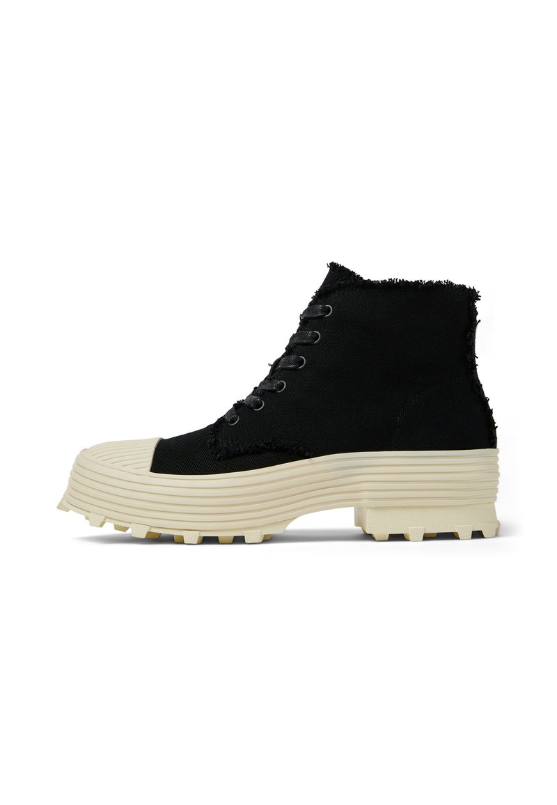 Scarpe alte nere con bordi sfrangiati, dotate di punta rotonda, suola in gomma testurizzata e piattaforma chunky beige con scanalature per la trazione.