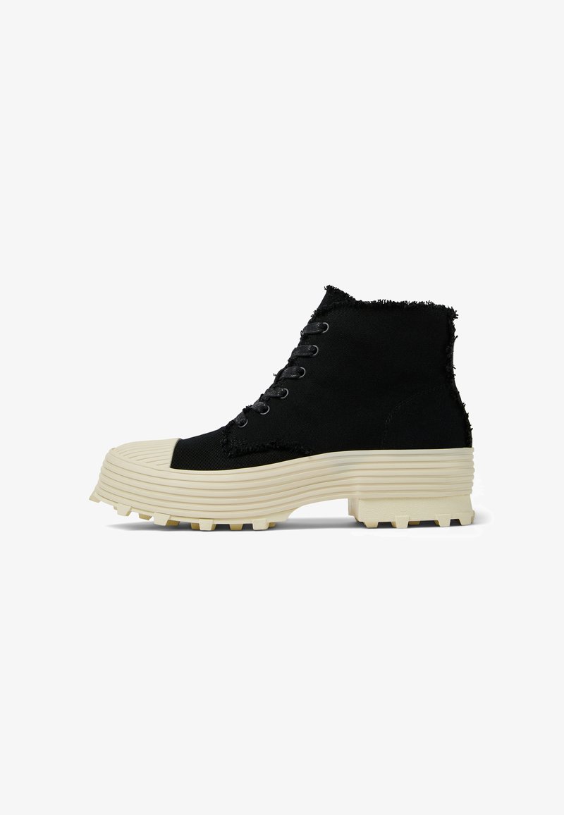 Scarpe alte nere con bordi sfrangiati, dotate di punta rotonda, suola in gomma testurizzata e piattaforma chunky beige con scanalature per la trazione.