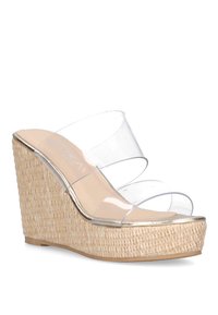 Sandalias de cuña con parte superior de plástico transparente y suela con textura similar a la paja, que cuentan con acentos en tono dorado y un diseño de plataforma.