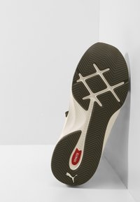 Sneaker with a textured white upper, brown rubber outsole, and red "IGNITE" accent. Features zigzag traction pattern for grip and stability.