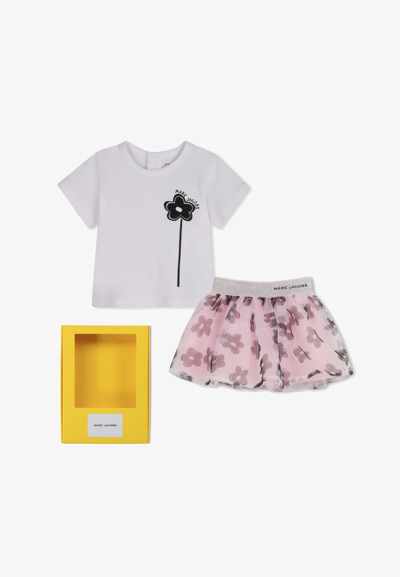 Λευκό πουκάμισο με κοντά μανίκια, μαύρο γραφικό λουλούδι και φούστα από ροζ τούλι με λουλουδάτο μοτίβο και γκλίτερ στη μέση, παρουσιασμένα με κίτρινο κουτί Marc Jacobs.