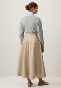 Beežist A-lõikega maksiseelik kõrge talje ja siledas tekstuuris, kombineeritud helehalli kampsuniga. Neutraalsetes toonides minimalistlik disain.