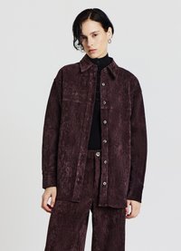 Camicia in velluto a coste color granata con chiusura frontale con bottoni, collo ampio e maniche lunghe, caratterizzata da una finitura testurizzata e una sottile lucentezza.