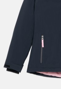 Giacca impermeabile blu navy con tasca con zip dotata di un tirante rosa, polsini testurizzati e rivestimento interno rosa a contrasto.