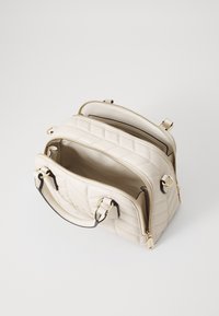 Puderfarvet quiltet taske med guldfarvet hardware, dobbelte lynlåse og kontrasterende sorte detaljer. Har to rum og top hanke.