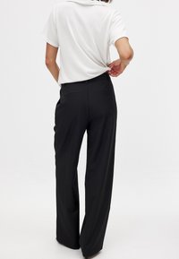 Melnas platās bikses ar gludu tekstūru un divām aizmugurējām kabatām, apvienotas ar baltu īsajām piedurknēm. Vienkāršs, klasissks dizains.