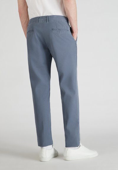 Pantalon droit bleu clair avec une texture lisse, doté de deux poches arrière et d'une taille avec passants de ceinture. Associé à des baskets blanches.