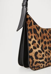 Borsa a tracolla in stampa leopardata con pelliccia sintetica marrone e nera, accenti in pelle nera e una tracolla piatta. Caratterizzata da un distintivo motivo animale.