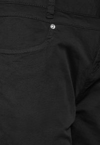 Svarta denimjeans med en klassisk femfickdesign, med en synlig metallknappdetalj och slät textur.