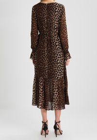 Leopardmönstrad midiklänning i genomskinligt tyg, med långa ärmar, insvängd midja och lager-på-lager nederkant. Matchas med svarta sandaler med remmar.