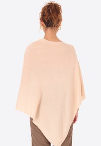 Poncho color beige chiaro con design drappeggiato, realizzato in materiale morbido. Presenta una silhouette a taglio ampio e una texture sottile, che si restringe ai bordi.