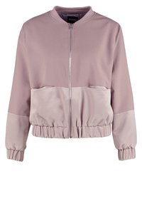 Veste bomber mauve clair avec fermeture éclair à l'avant, col côtelé assorti et poignets élastiques. Présente un panneau lisse semblable à de la satin au niveau de la taille.