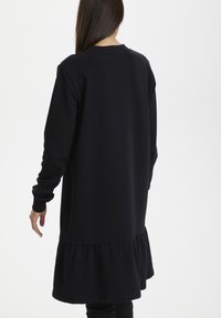 Robe sweat-shirt noire à manches longues, ourlet à volants et encolure ronde, confectionnée dans un tissu doux, avec une coupe décontractée.