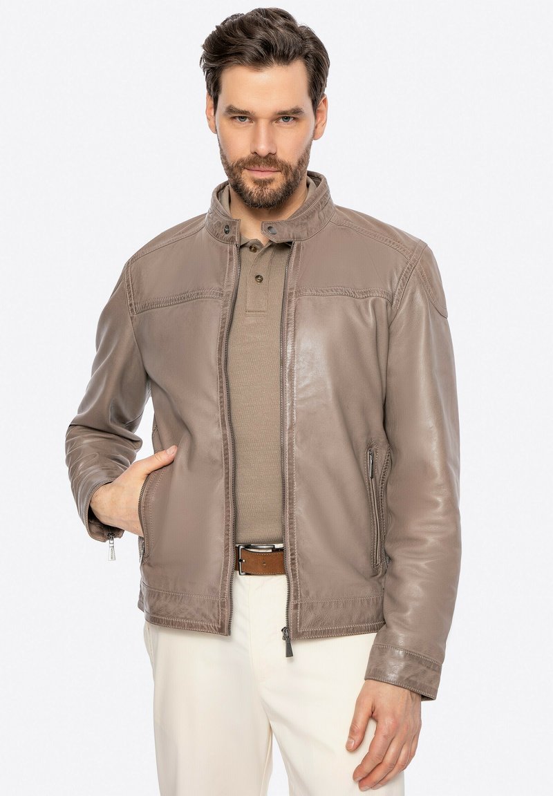 Giubbotto in pelle marrone con colletto alto, chiusura con zip e tasche laterali. Tessuto liscio con dettagli cuciti e vestibilità casual.
