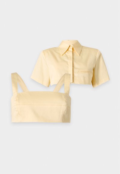 Ensemble haut deux pièces jaune clair avec une chemise courte à manches courtes et col, et un débardeur court assorti avec bretelles.