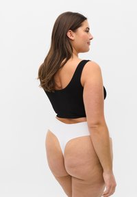 Czarny dopasowany crop top i biały wysoko wycięty thong, gładki materiał, jednolite kolory, prosty design, zaprezentowane z boku na jednolitym tle.