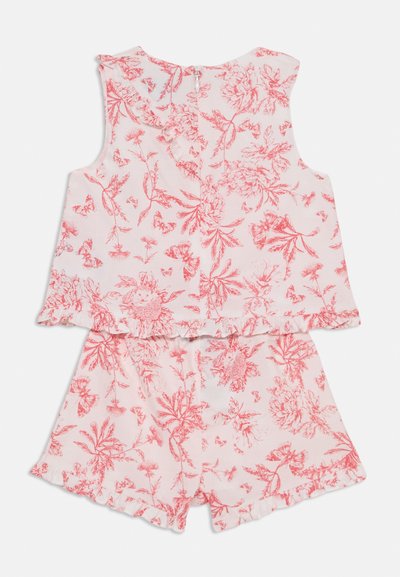 Blommig tvådelad outfit i ljusrosa med röda blommor och fjärils mönster. Topp har volangade axlar och bakdragkedja; shorts har volang i nederkant.