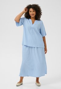 Light blue two-piece outfit featuring a textured, loose-fitting top with a V-neck and short sleeves, paired with a matching long skirt.