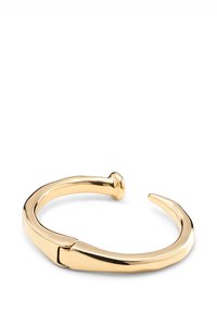 Brazalete de metal con tono dorado y acabado liso y brillante. Presenta un diseño curvado con un extremo puntiagudo y un detalle de cierre redondeado.