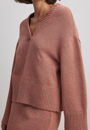 Terracotta V-Ausschnitt-Pullover mit geripptem Saum und Bündchen, präsentiert ein strukturiertes Strickmuster. Lässige Passform mit überschnittenen Schultern für einen hohen Tragekomfort.