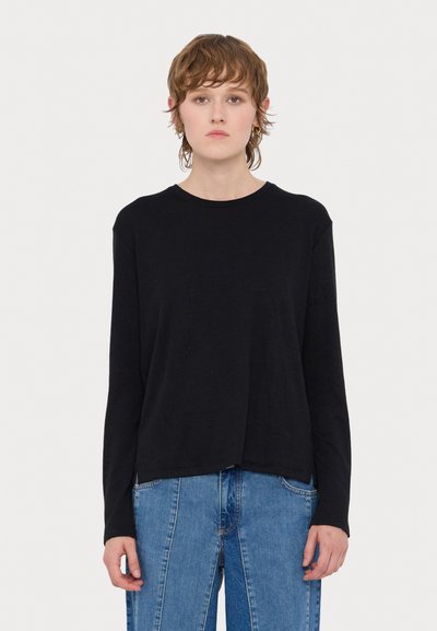 T-shirt noir à manches longues en tissu doux, avec un col rond, une coupe décontractée et des fentes latérales à l'ourlet pour un meilleur confort de mouvement.