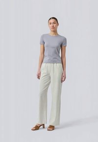 Light gray fitted t-shirt paired with cream striped wide-leg pants and brown block-heeled sandals. Simple design with comfort-focused materials.