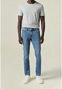 Szara koszulka z okrągłym dekoltem, jasnoniebieskie jeansy oraz białe trampki. Gładka tekstura tkaniny, standardowy krój i minimalistyczny design.