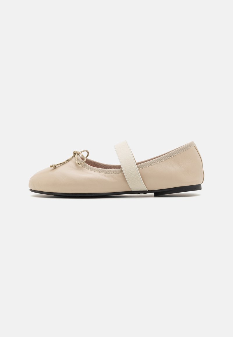 Beige Leder Ballettschuhe mit runder Zehenpartie, elastischem Knöchelriemen und dekorativem Schleifen-Detail. Glatte Textur und minimalistisches Design.