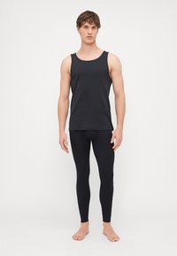 Μαύρο αμάνικο μπλουζάκι και κολάν εφαρμοστό από λείο ύφασμα, με μινιμαλιστικό σχέδιο χωρίς μοτίβα ή ορατά αξεσουάρ.