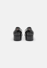 Black patent leather shoes with a low block heel, rounded toe, and a small logo detail on the back. Smooth, shiny surface texture.