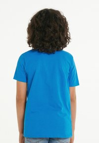 Modrá bavlněná tričko s kulatým výstřihem a krátkými rukávy, s hladkým povrchem a jednoduchým designem, z pohledu zezadu.