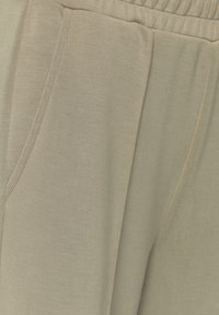 Lichtbeige joggingbroeken van zachte stof, met een elastische tailleband en zijzakken. De textuur is glad met subtiele stikseldetails.