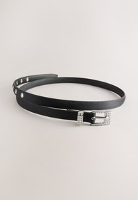 Svart läderbälte med smal design, utrustat med ett glänsande spänne dekorerat med strass och metalldetaljer längs remmen för justerbar passform.