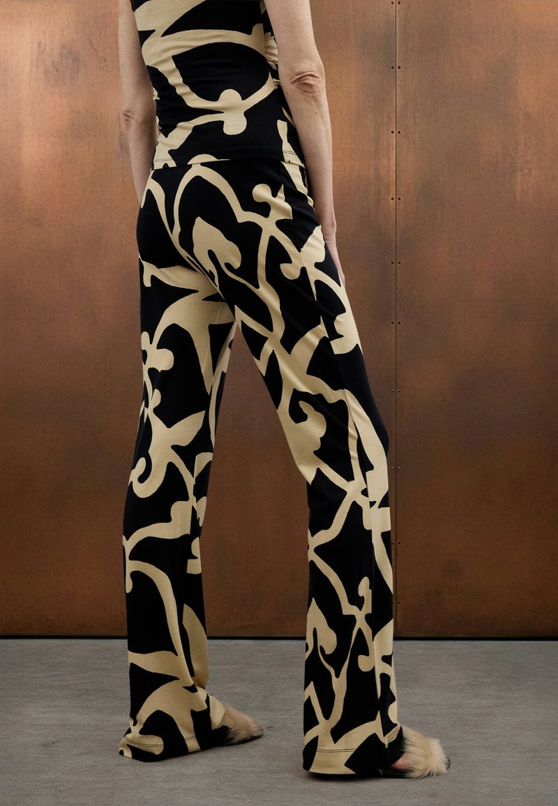 Zwart-beige broek met patroon en vloeiend ontwerp, gemaakt van zachte stof, met een hoge taille en een uitlopende pijp.