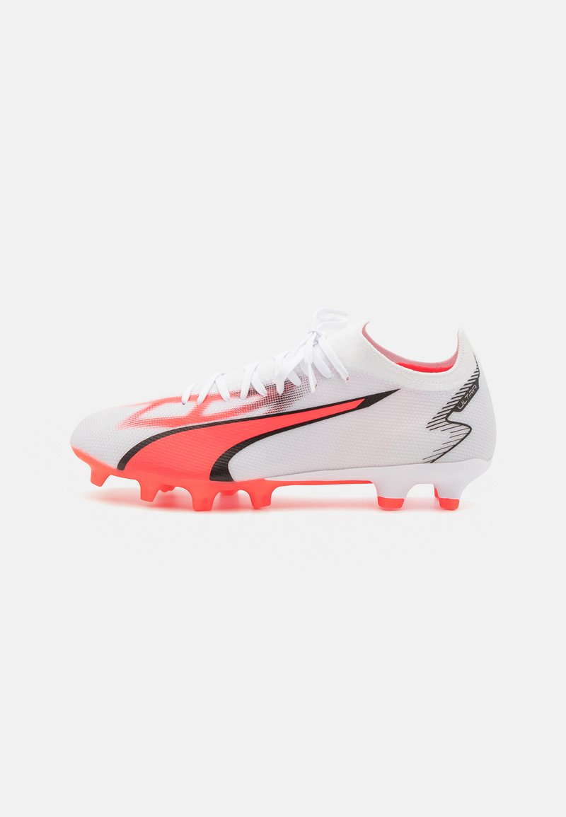 Scarpa da calcio bianca con un design rosso e nero, tomaia in rete, punta rotonda e tacchetti arancioni per la presa su superfici erbose.