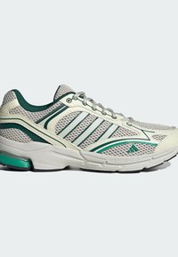 Mesh running shoe in light grey with green accents. Features a textured surface, six eyelets, and cushioned sole with adiPRENE technology.
