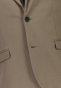 Blazer marrón hecho de tejido texturizado, que cuenta con un único botón negro, dos bolsillos delanteros y un ligero brillo. Corte entallado con líneas limpias.
