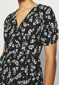 Černé šaty s výstřihem do V a nafouknutými rukávy. Mají květinový vzor v světle modré a krémové barvě na texturované látce.