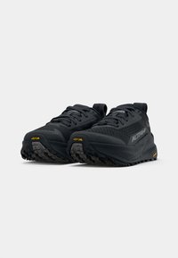 Ténis de corrida pretos com uma parte superior em malha, acabamento texturizado, sistema de atacadores proeminente e sola Vibram para tração. Detalhes em amarelo.