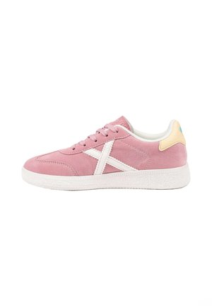 Zapatilla de ante rosa con detalle X blanco en el lateral, suela blanca, cordones rosas y lengüeta del talón beige con acento en verde azulado, vista desde el lado exterior.