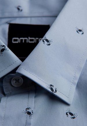 Camicia blu chiaro con una stampa di piccoli granchi neri. Il tessuto è liscio, con colletto classico e chiusura con bottoni.