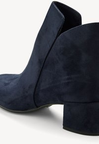 Bottine en daim bleu marine avec un petit talon bloc et une ouverture avant en forme de V sur fond blanc.