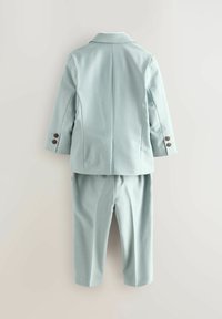 Svetlo modra otroška obleka z blazerjem, ki ima na vsakem rokavu dva gumba, in ujemajoče hlače z ravnimi nogami, prikazana od zadaj.