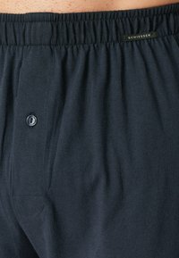 Pantaloni boxer in cotone blu navy con cintura elastica, dotati di una chiusura a bottone singolo e un dettaglio di tasca cucita.