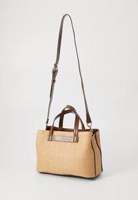 Sac à main tissé en paille avec des poignées en cuir marron et une bandoulière réglable. Présente une forme structurée et une texture lisse.