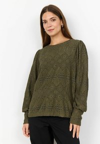 Blusa a maglia verde oliva con motivo a diamante testurizzato, maniche lunghe a sbuffo e scollo rotondo. Abbinata a pantaloni neri.
