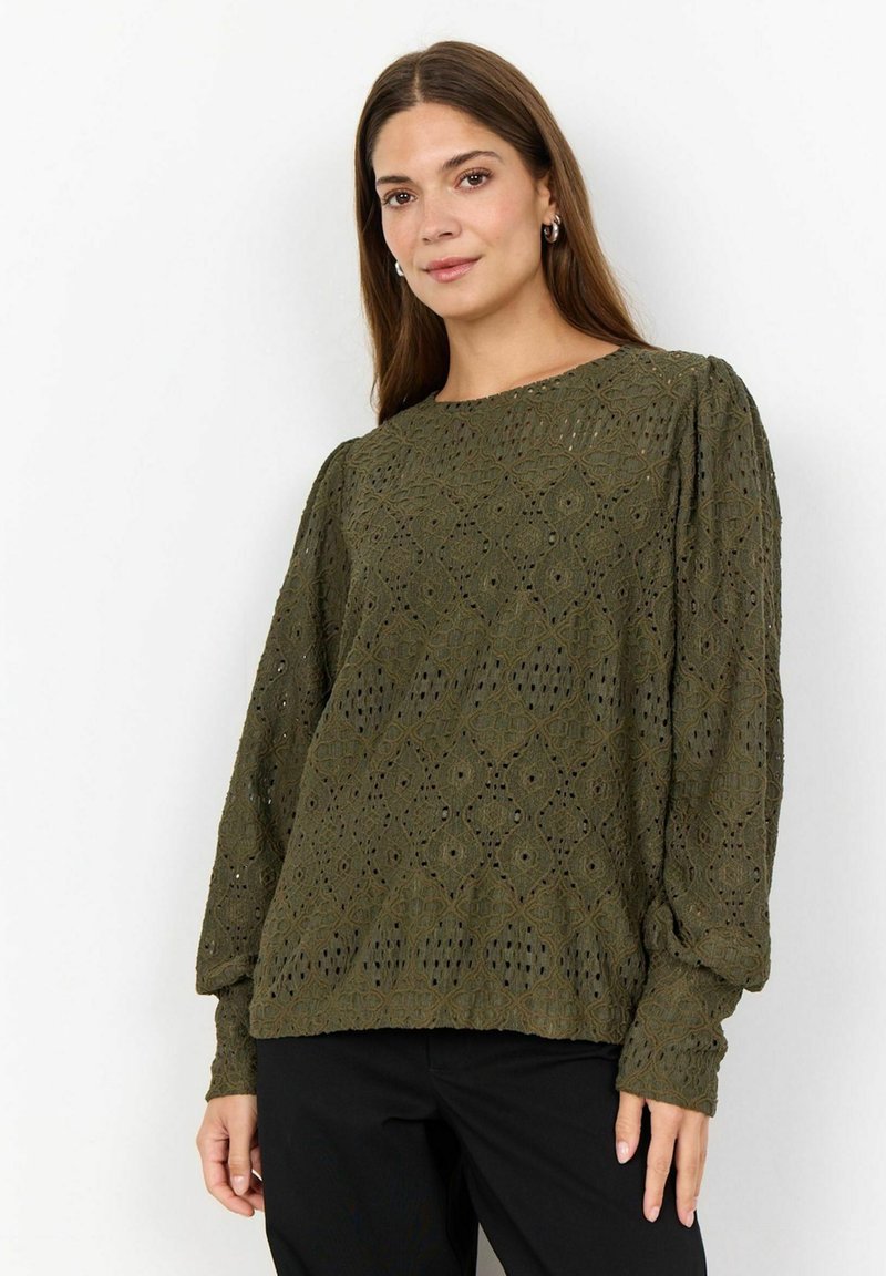 Blusa a maglia verde oliva con motivo a diamante testurizzato, maniche lunghe a sbuffo e scollo rotondo. Abbinata a pantaloni neri.