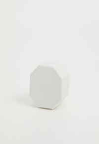 White octagonal container made of textured material with a subtle logo on top. Features a slightly raised edge and smooth surfaces.