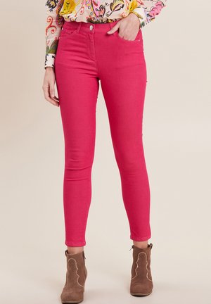 Roze skinny jeans met een gladde textuur, vijf-pocketontwerp en zilveren hardware, gecombineerd met bruine enkellaarsjes met gegolfde randen.