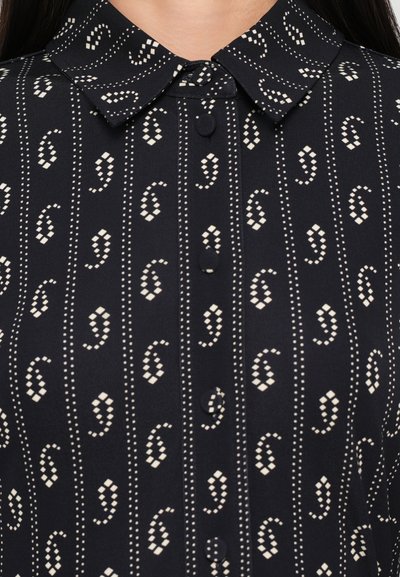 Camicia colletto blu scuro con un motivo astratto ripetuto di colore chiaro che presenta piccole forme di diamante e accenti circolari, chiusa con bottoni.